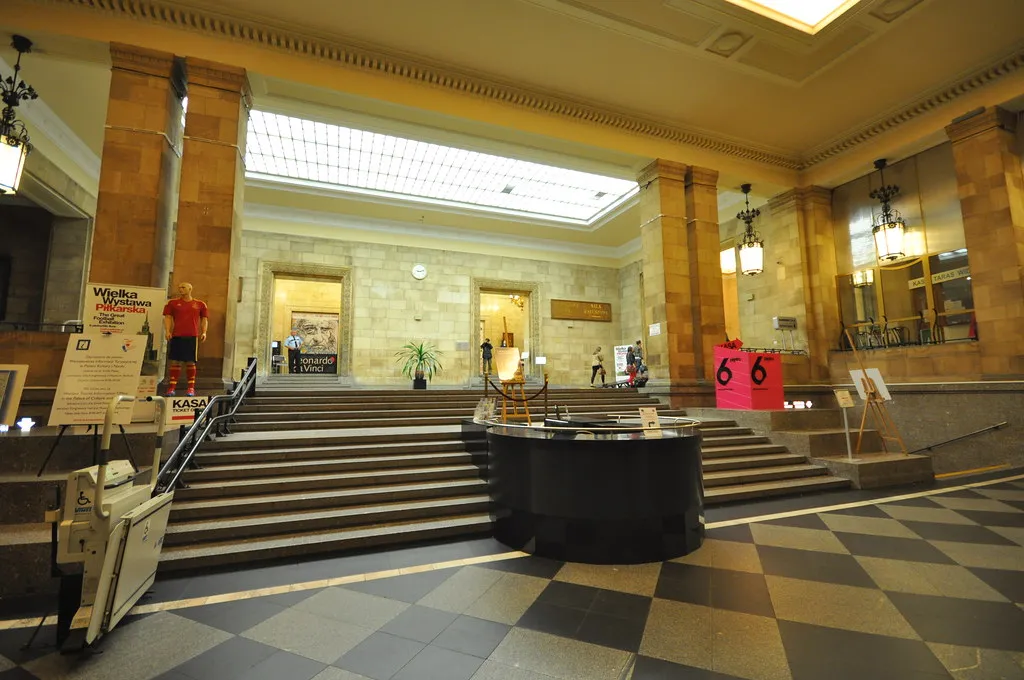 Grand commercial lobby with a checkerboard stone floor and stone-clad columns