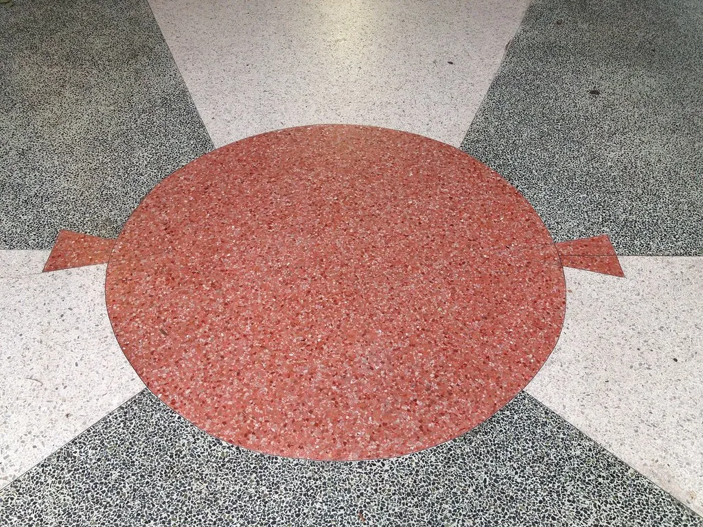 Art-deco terrazzo floor with a red medallion and radiating pattern