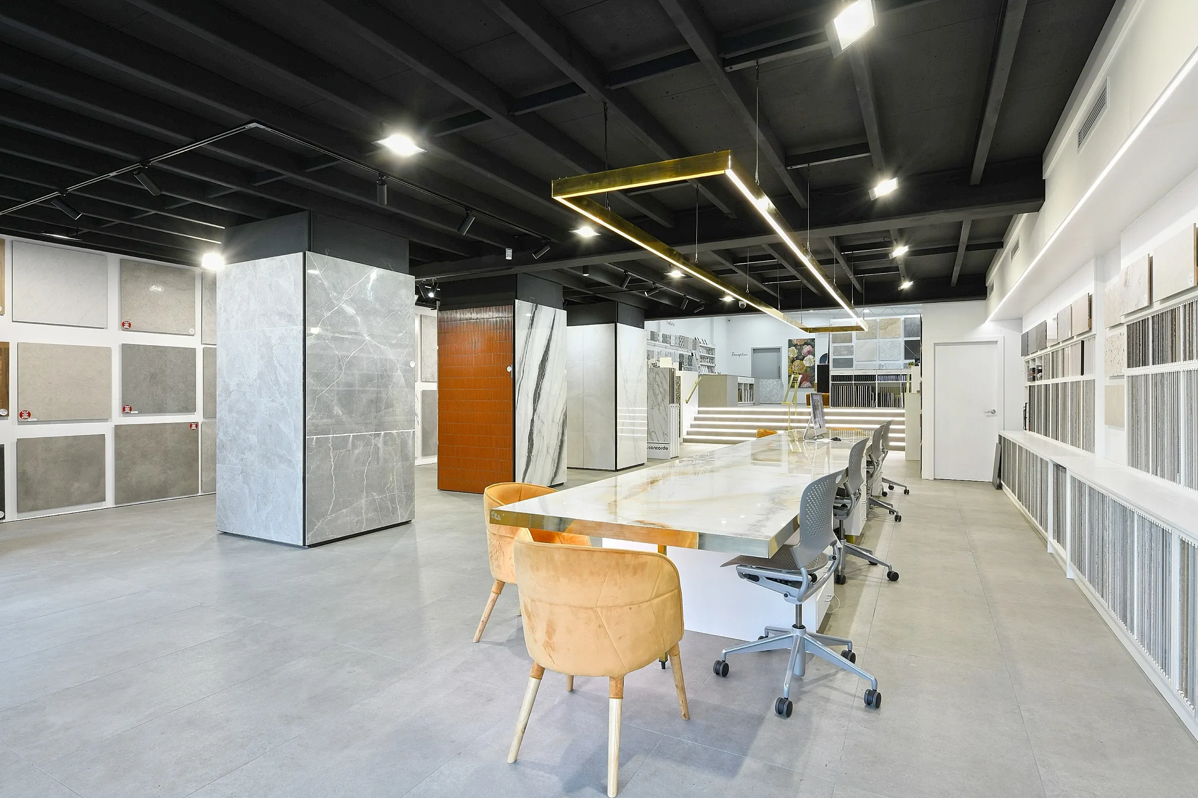 Interior of a tile and stone design showroom with slab displays and a consultation table