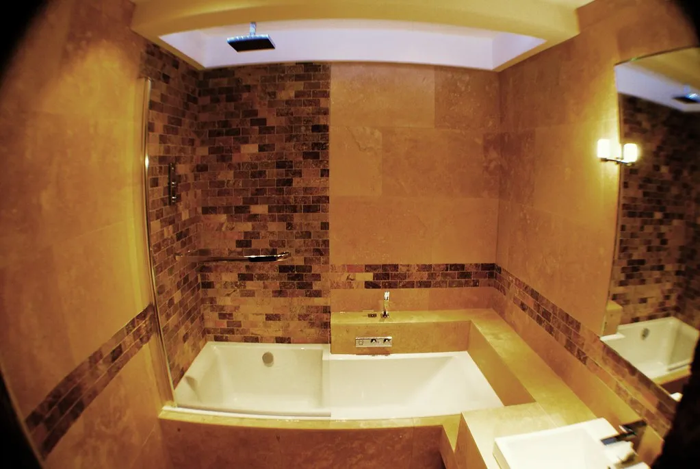 Travertine tub surround with a stone mosaic feature band around the bathtub