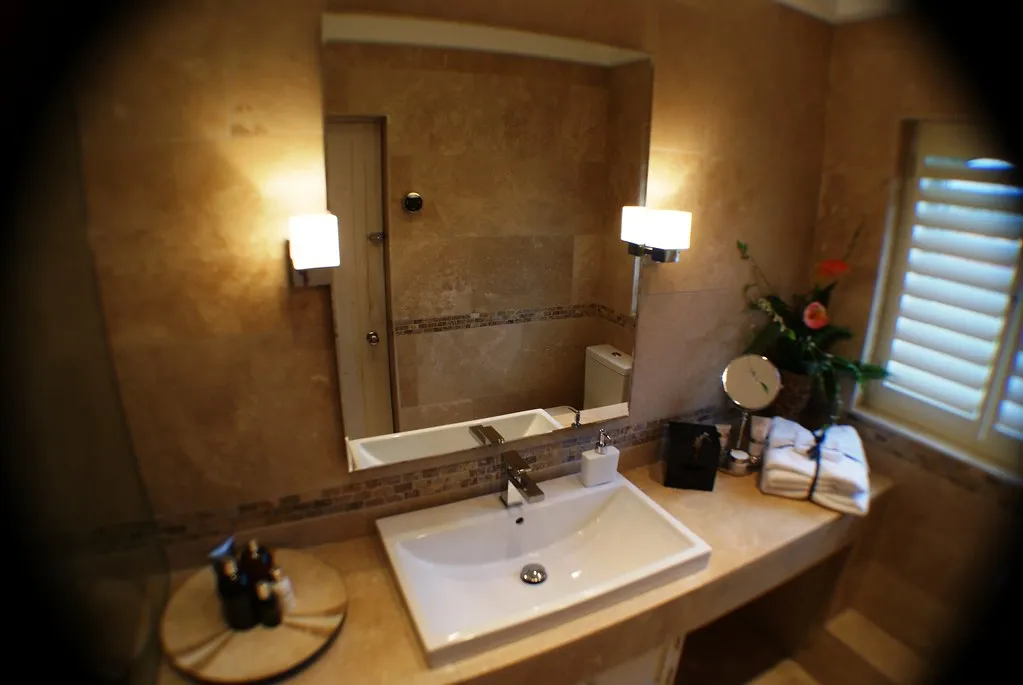 Travertine-clad bathroom vanity wall with a mosaic stone accent band