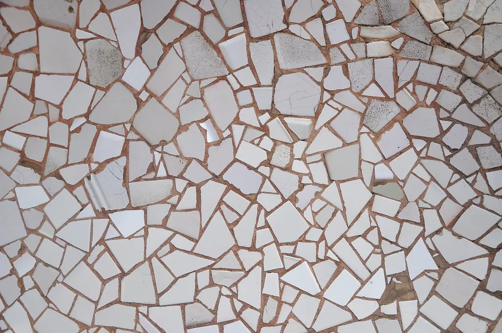 White broken-tile mosaic surface with terracotta grout lines