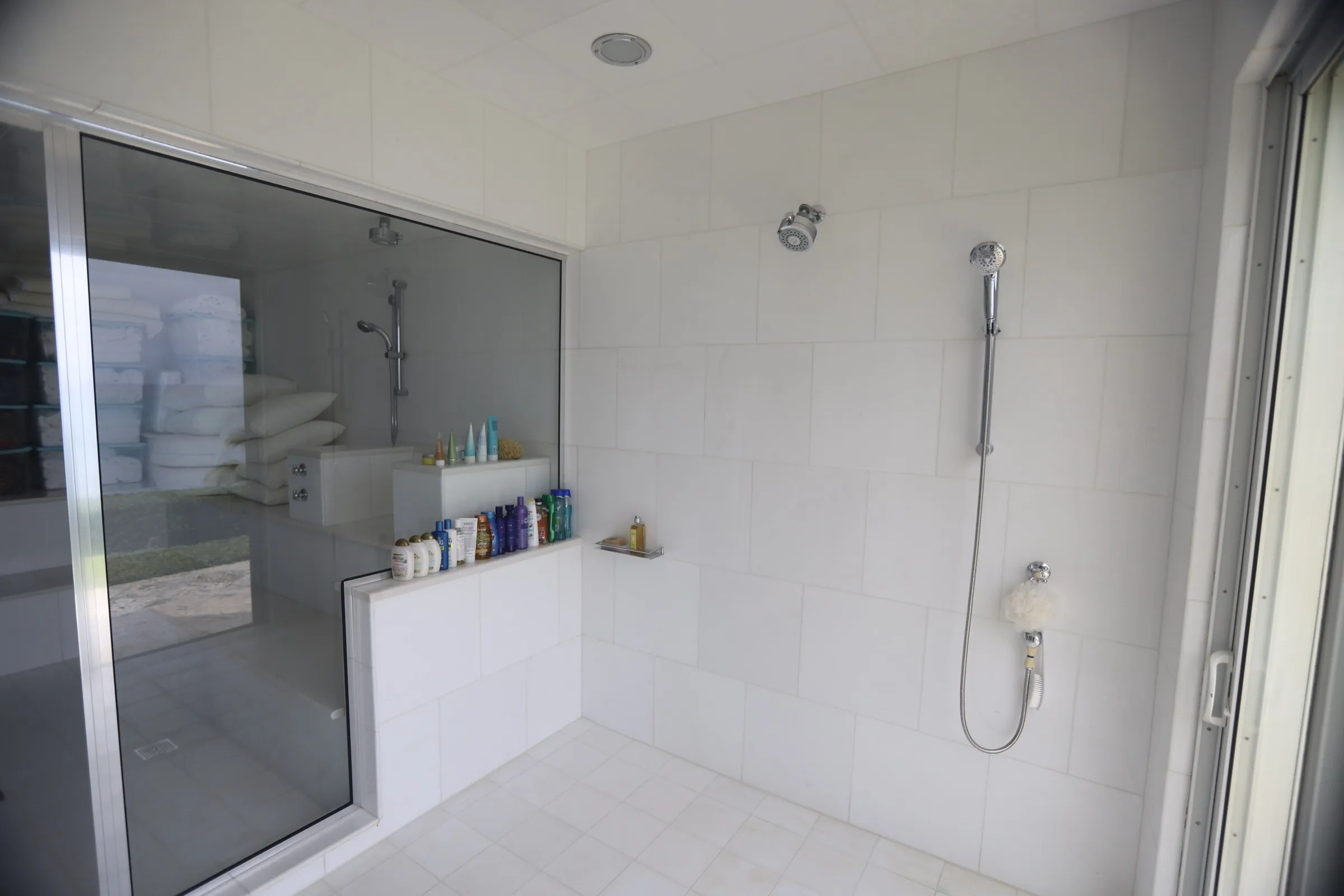 Large white-tiled walk-in shower with glass enclosure and a tiled bench